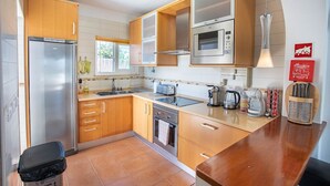 Una cocina moderna con armarios de madera, electrodomésticos de acero inoxidable, horno empotrado y cafetera.