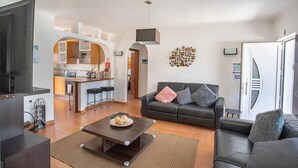 Una sala moderna con un sofá, una mesita de centro y una cocina al fondo.