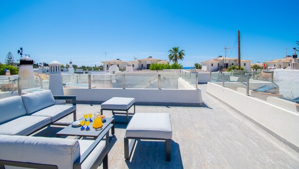 Une terrasse sur le toit avec des sièges extérieurs, une piscine et une vue dégagée sur les bâtiments environnants.