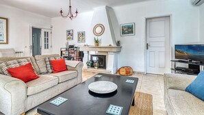 Una sala de estar con sofá, mesa de centro, chimenea, televisor y estantería.