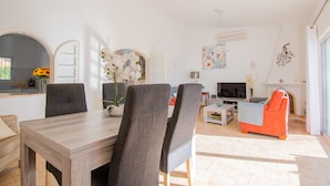 Una sala de estar moderna con comedor, un sofá y un televisor.