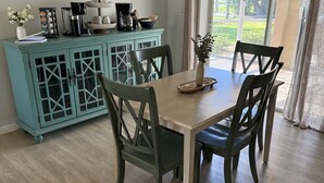 A dining area with a teal cabinet, wooden chairs, and a coffee bar sign on the wall. - Relax at Cape Palm Oasis (Cape Coral)