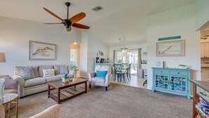 A spacious living room with a ceiling fan, a sofa, a coffee table, and a dining area with a table and chairs. - Relax at Cape Palm Oasis (Cape Coral)