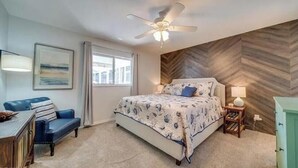 A bedroom with a bed, a desk, a chair, a ceiling fan, and a herringbone-patterned wall. - Relax at Cape Palm Oasis (Cape Coral)