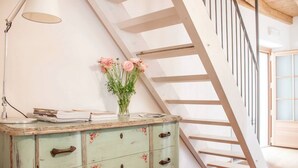 Una escalera con barandilla de madera y pared de color claro.