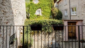 Un patio con pared de piedra, valla metálica y una mesa con sillas.