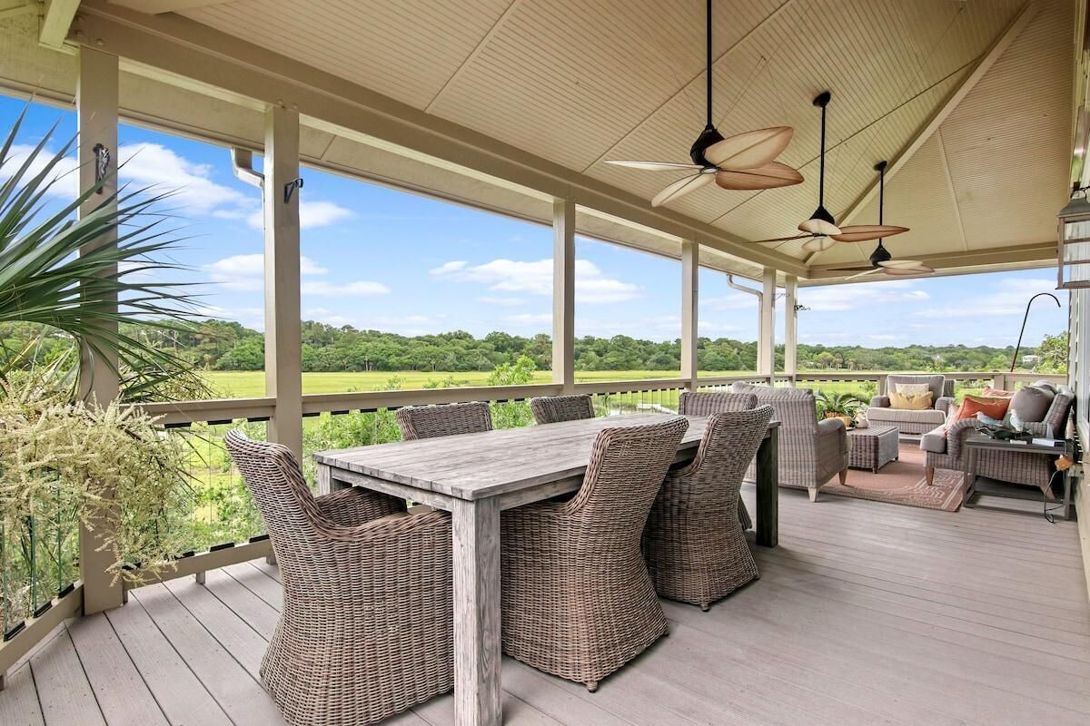 Eine überdachte Terrasse im Freien mit einem Holztisch und Korbstühlen, mit Blick auf eine üppige grüne Landschaft.