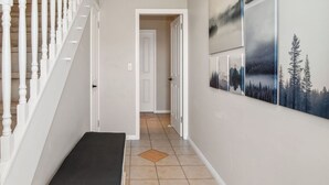 Un escalier avec des balustrades en bois, une moquette noire et un couloir menant à une porte.