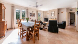A spacious living area with a dining table, chairs, a sofa, and a TV.