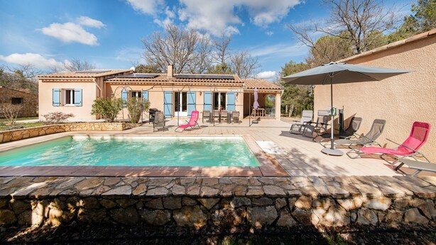 A house with a swimming pool, outdoor seating, and a stone wall.