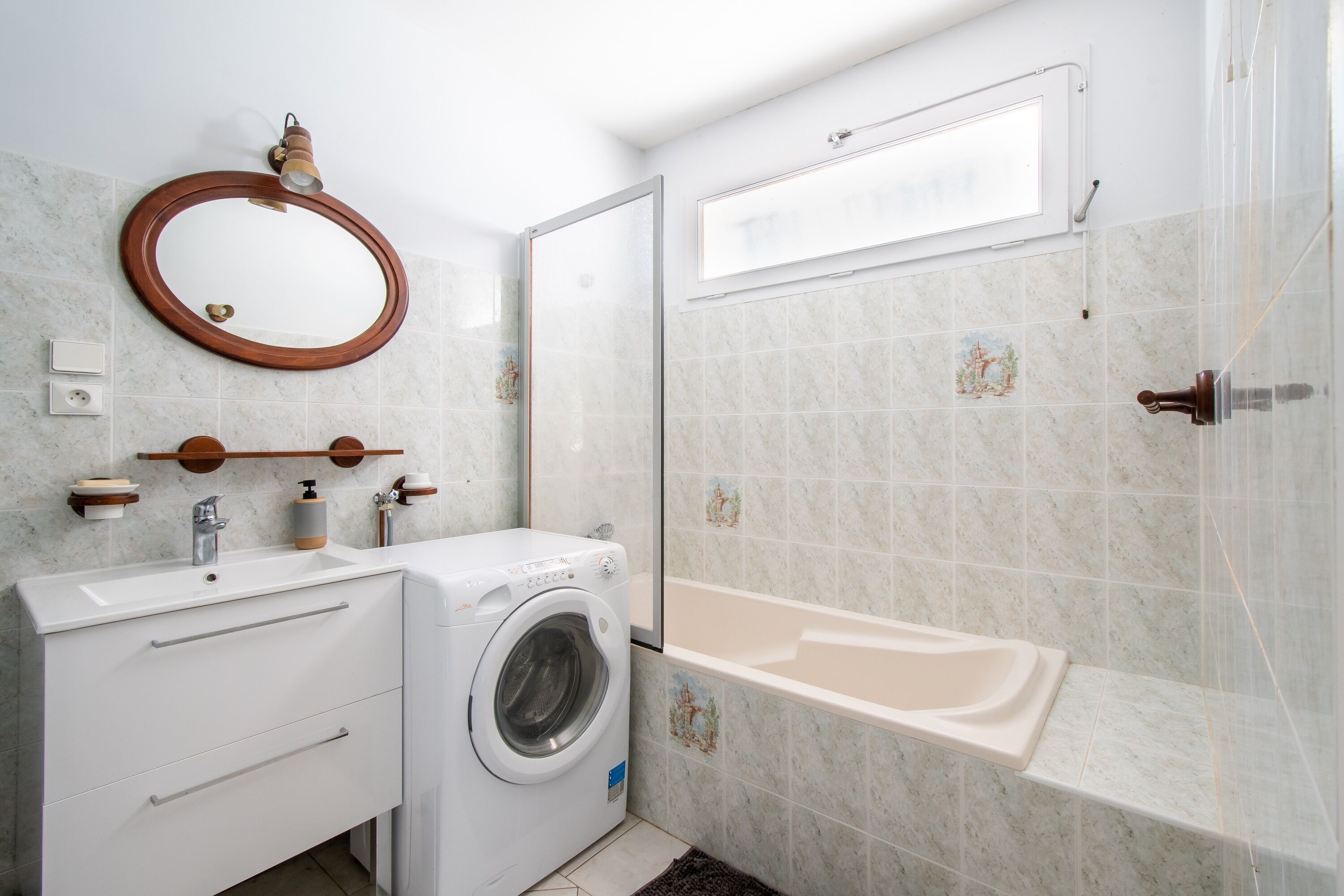 Une salle de bain moderne équipée d’un lave-linge intégré, d’un lavabo et d’une baignoire.