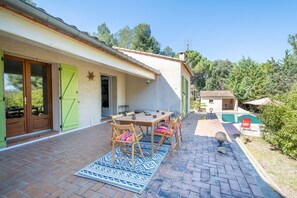 Un patio con una mesa y sillas de madera, un tapete estampado y una pequeña esfera decorativa.