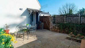 Un patio con tavolo e sedie, un piccolo portone e una recinzione in legno.
