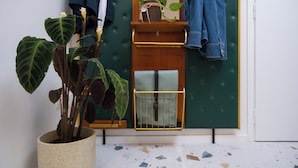 A room with a potted plant, a mirror, a hanging bag, and a denim jacket on a wall-mounted rack. - Ruby's Urban Residence Koukaki (Athens)