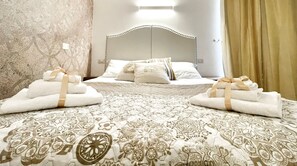 A hotel room with a bed, two sets of towels, a patterned bedspread, and a plain wall. - BARI ROOMS Abate Gimma (Bari)