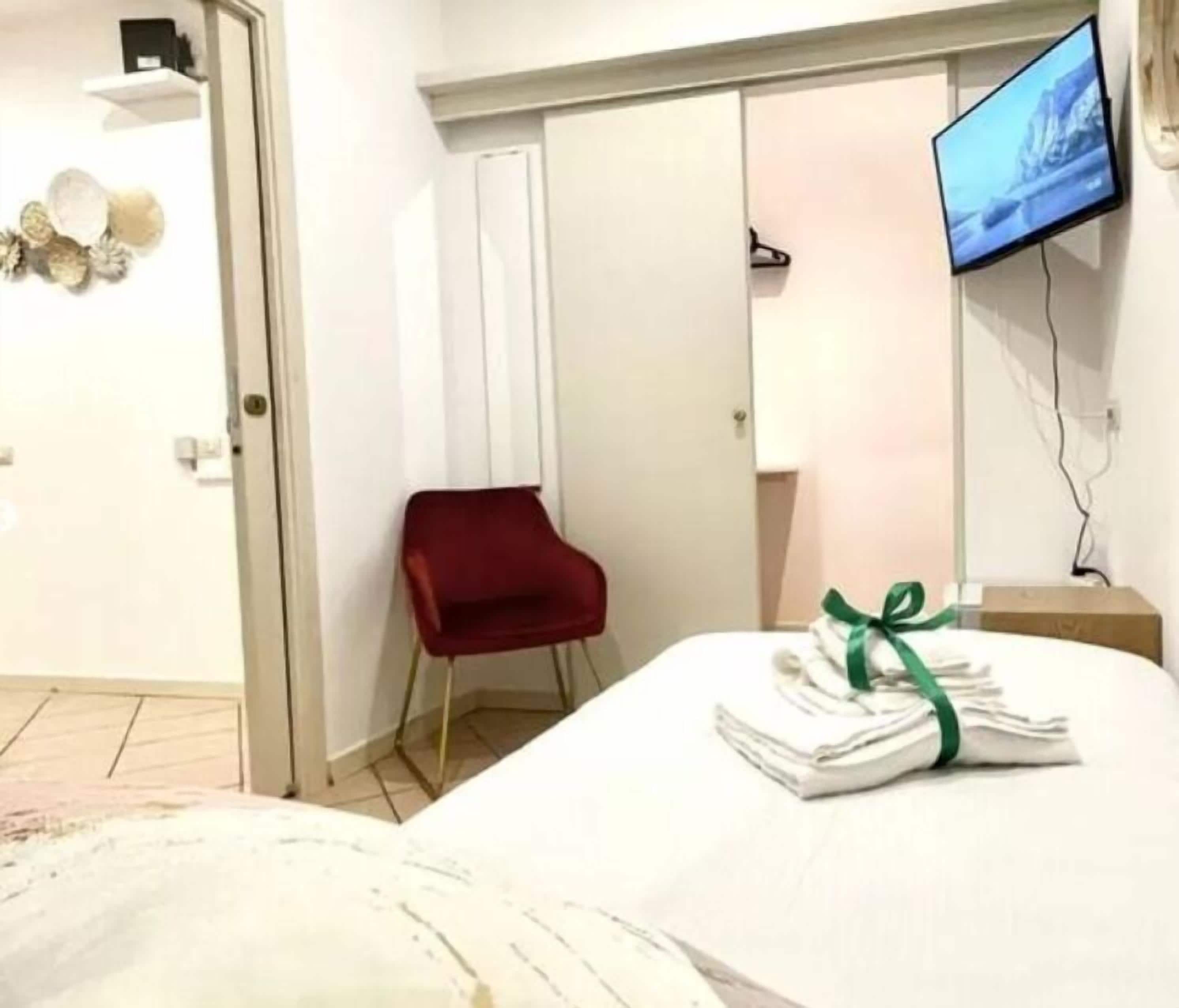 Ein Hotelzimmer mit einem Bett, einem roten Sessel, einem Fernseher und einer Tür.