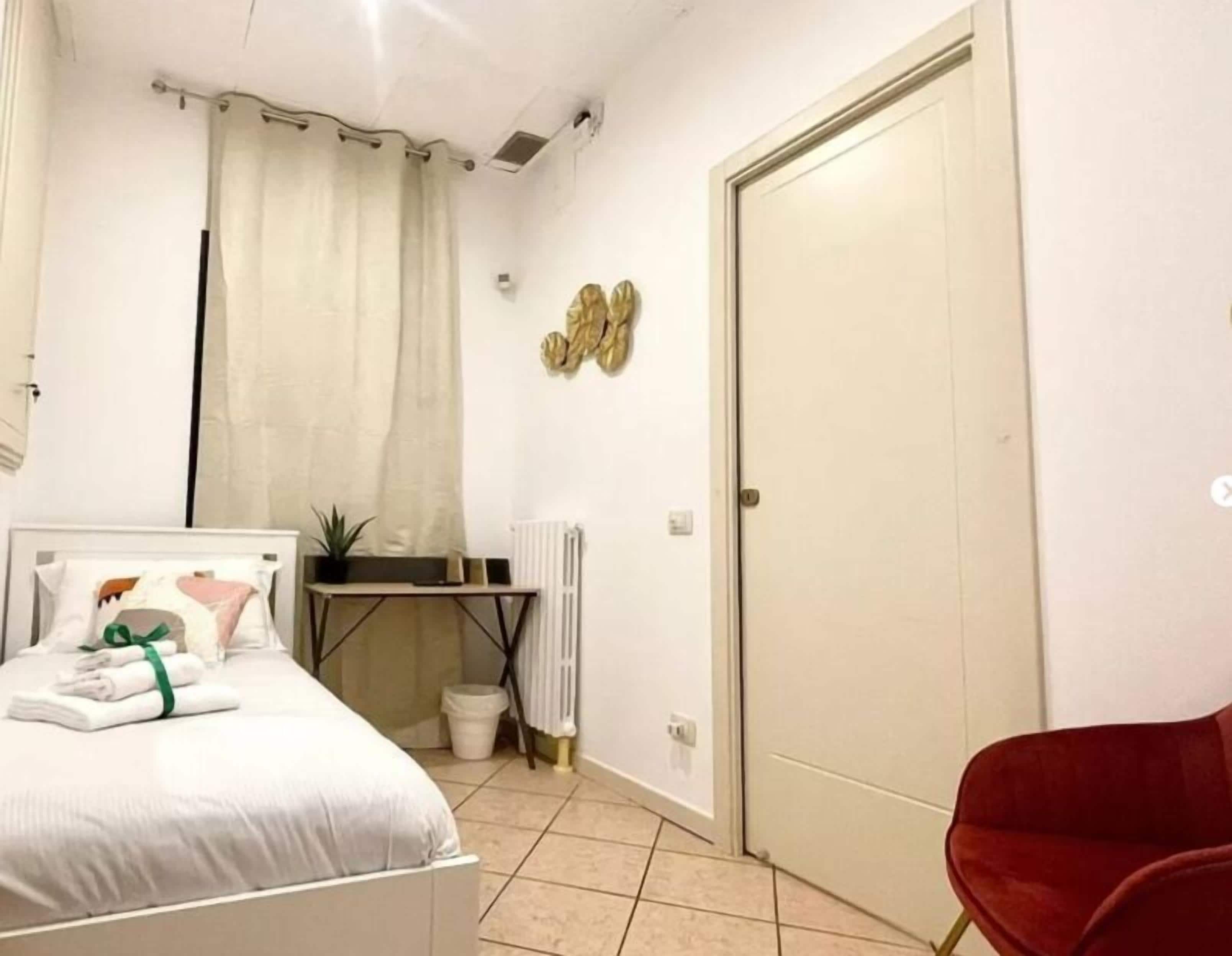 A bedroom with a bed, a desk, a chair, a radiator, and a door.