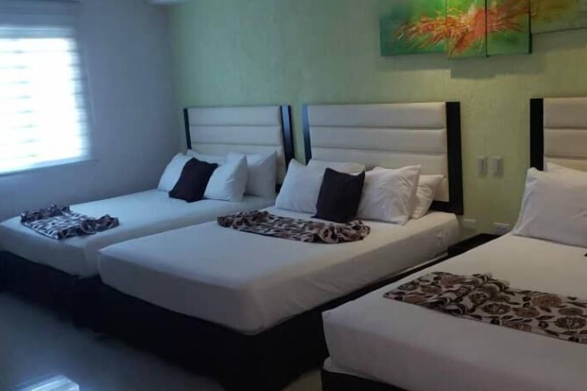Een hotelkamer met twee enkele bedden, elk met hoofdeinde, kussens en een gestreept deken.