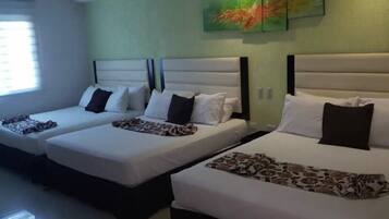 A hotel room with two single beds, each with a headboard, pillows, and a patterned blanket.