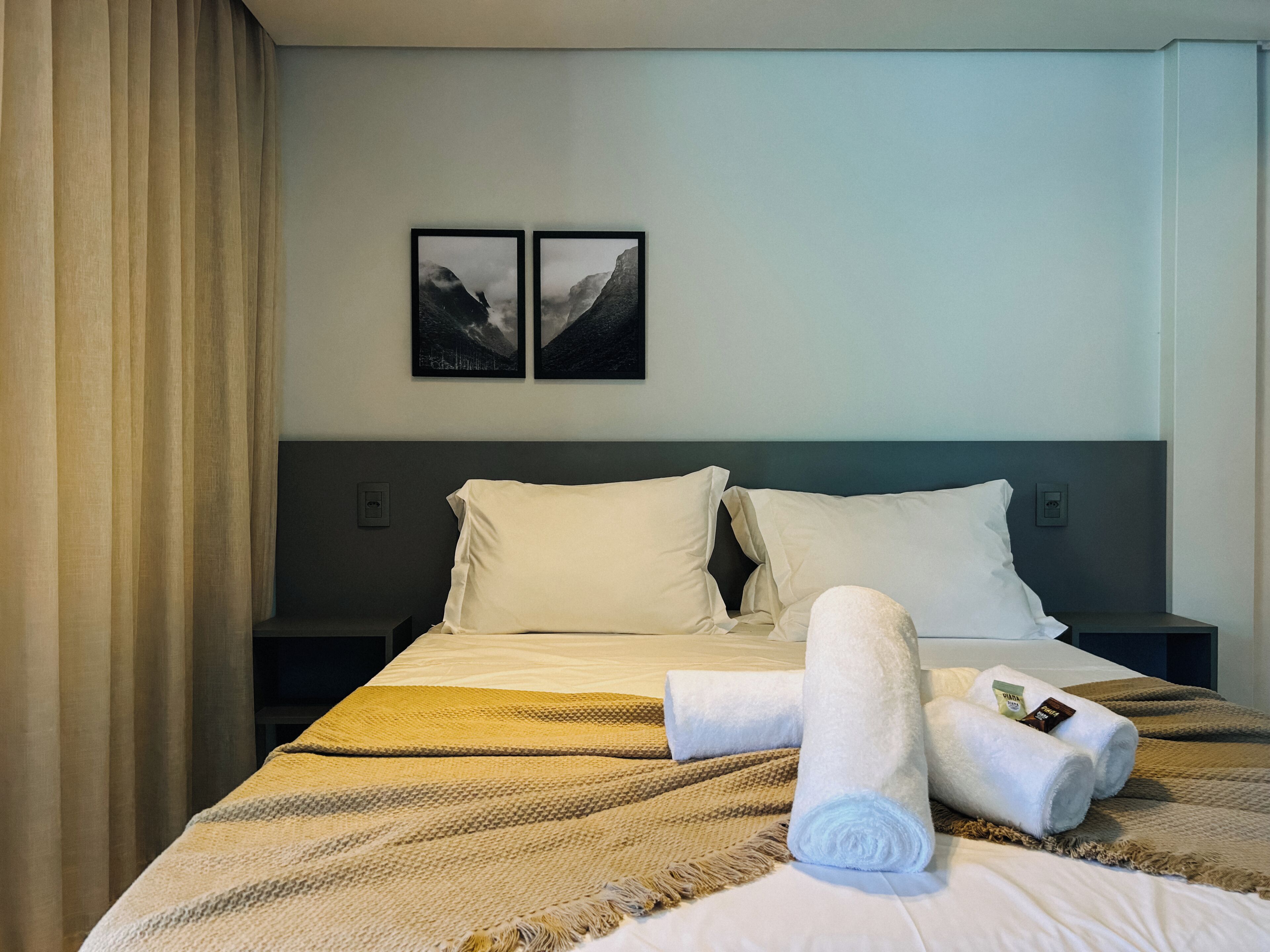Une chambre d’hôtel avec un lit, deux oreillers, une couverture et deux serviettes.