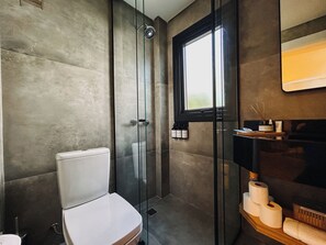 Un bagno moderno con doccia vetrata, un water e una finestra.
