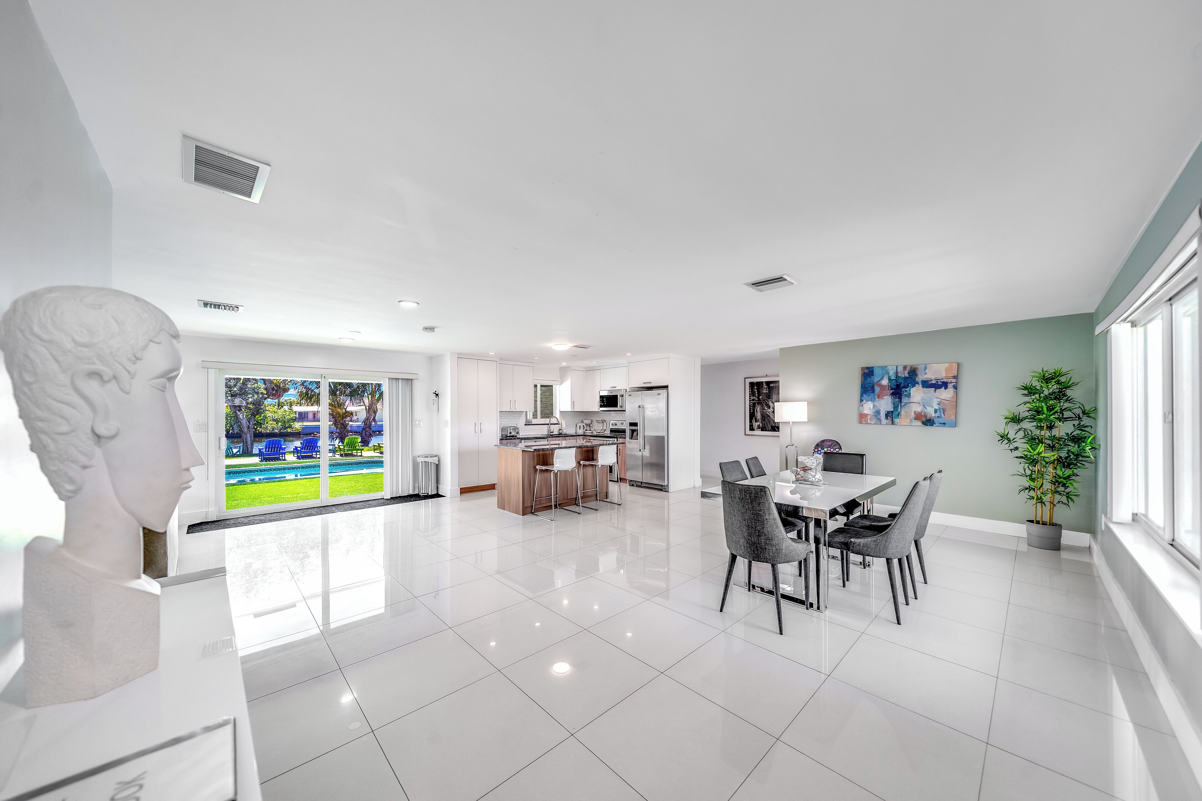 A modern kitchen with white cabinets, a central island, and a dining area with a table and chairs.