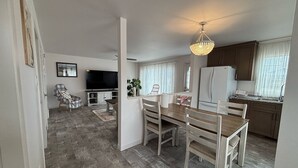 Una cocina moderna con armarios de madera, un refrigerador y un comedor con mesa y sillas.