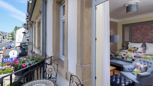 A hotel room with a balcony, a bed with a colorful duvet, a sofa, and a small table. - Hotel The Rose by Goeres (Luxembourg City)