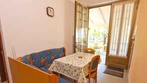 A small dining area with a table and chairs, a sofa, and a door leading to an outdoor area. - Holiday Home With Barbecue in Medulin (Medulin)