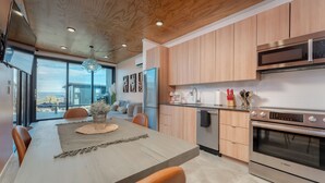 Eine moderne Küche mit Holzausstattung, einem Bosch-Ofen und einem großen Esstisch mit orangefarbenen Stühlen.