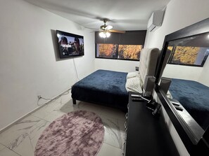 Relax in a cozy space with a comfortable bed, flat-screen TV, and ceiling fan.