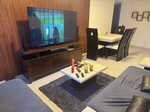 Relax in this stylish living room with a flat-screen TV, dining area, and comfortable seating.