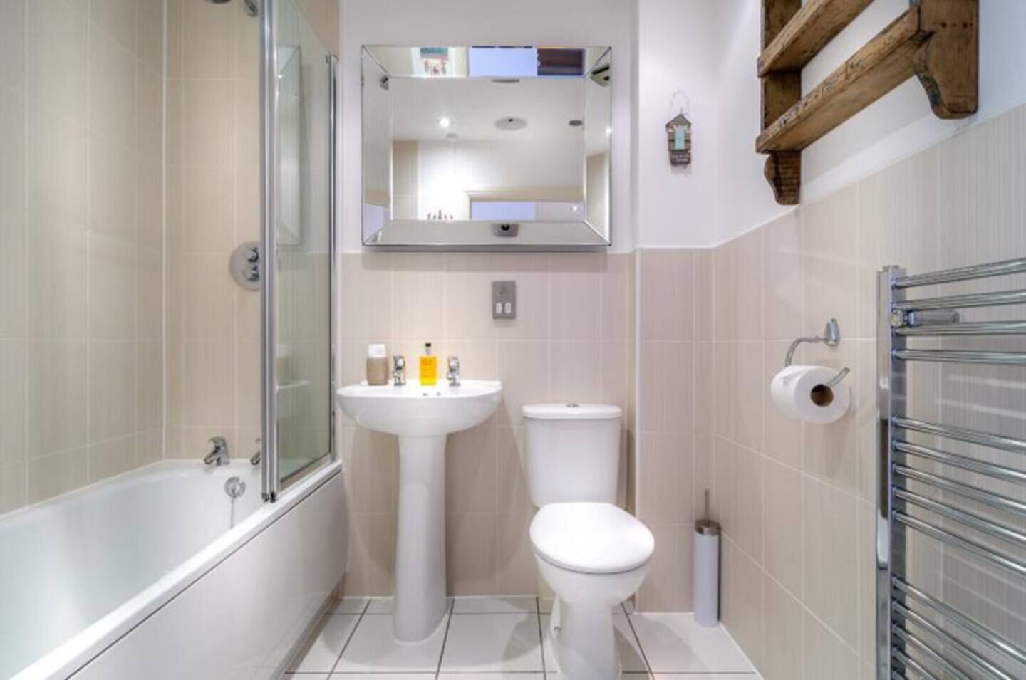 A bathroom with a bathtub, sink, toilet, and a mirror above the sink.