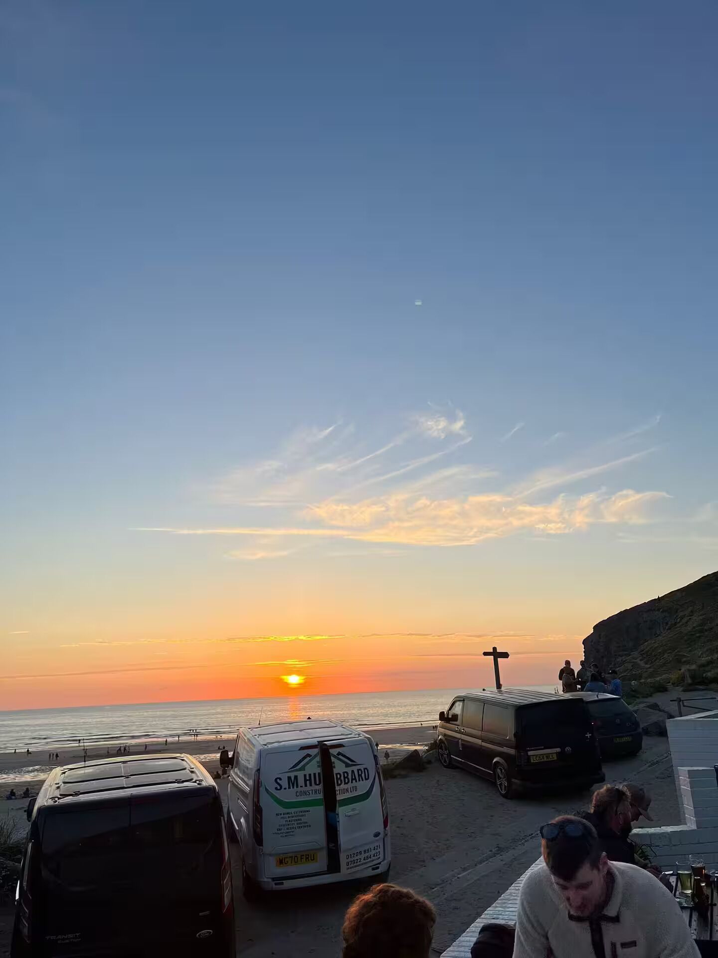 Ein Sonnenuntergang mit Strand, Fahrzeugen und Personen.