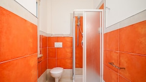 A bathroom with orange tiles, a white toilet, and a glass-enclosed shower. - BARIROOMS - PICCINNI (Bari)