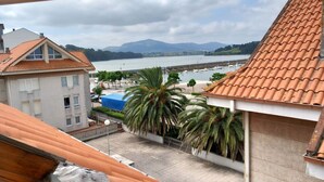 A view from a balcony overlooking a waterfront with buildings, a palm tree, and a body of water.