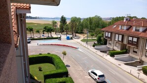 A residential area with a road, a white car, and a building with a tiled roof.