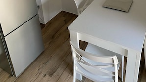 Une petite cuisine moderne avec un réfrigérateur blanc, une table blanche et une chaise blanche.