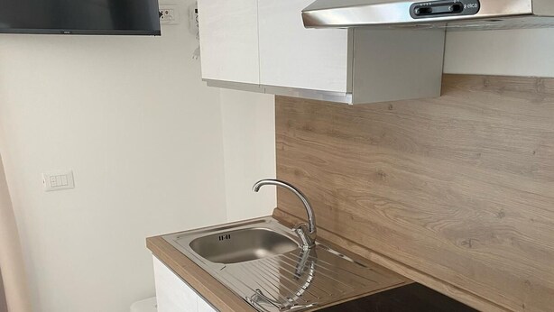 Une cuisine moderne équipée d’une cuisinière intégrée, d’un évier et d’un téléviseur à écran plat fixé au mur.