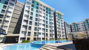 Un edificio residencial de varios pisos con balcones y una piscina.