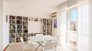 A spacious room with a white table and chairs, surrounded by bookshelves filled with books. - New Pop Art Suit with Parking (Unknown)