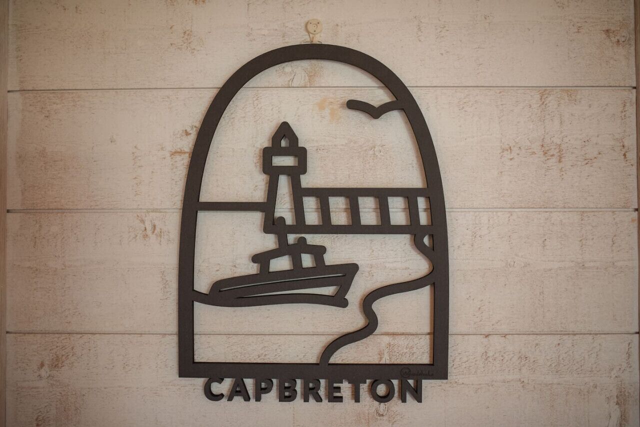 A wall-mounted sign with a lighthouse and ship design, labeled "CAPBRETON".