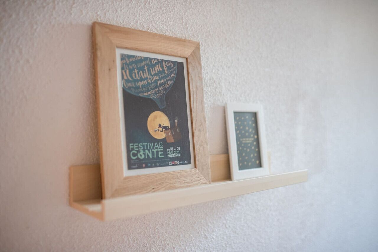 A framed poster on a wall with text and a moon illustration, and a smaller framed picture below it.