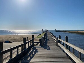 Un muelle de madera que se adentra en un mar tranquilo bajo un cielo despejado.