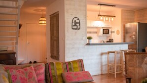 Un salon confortable avec un canapé, une table basse en bois et un coin cuisine équipé d’un four à micro-ondes et d’un réfrigérateur.