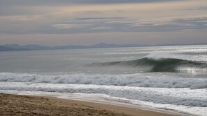 Une plage avec des vagues et une chaîne de montagnes qui se dessine à l’horizon.