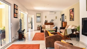 Amplia sala de estar con un conjunto de sofás, una mesa de centro y un televisor. Hay una puerta corrediza de vidrio que da a un balcón.