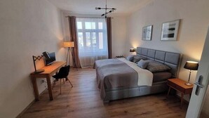 Een slaapkamer met een bed, nachtkastjes, een bureau en een stoel.