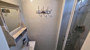 Een badkamer met een betegelde douche, een wastafel en een spiegel.