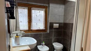 A bathroom with a sink, bidet, toilet, and a window with curtains. - Charming chalet with WiFi and AC in lovely Rubano (Rizzi)